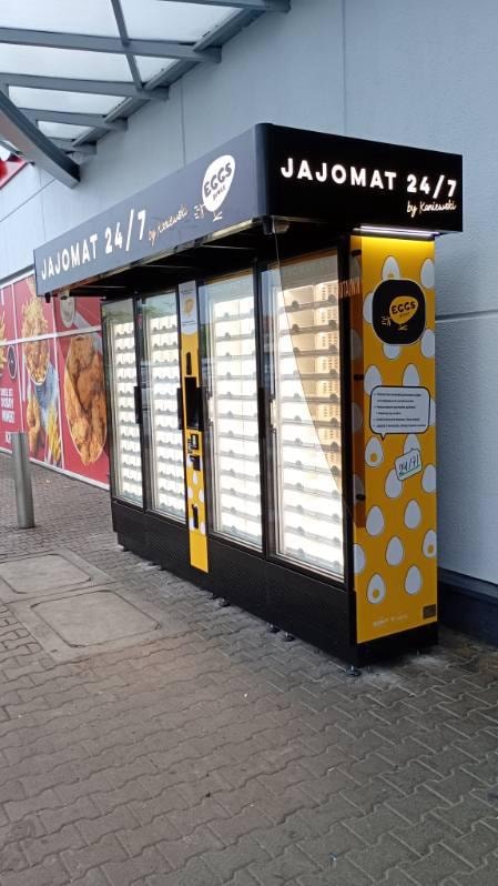 Distributeur jaune d’œufs sous un abri près d’une boutique